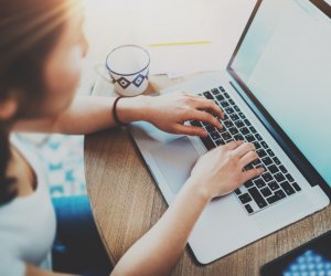 Closeup of woman surfing web at living room on modern computer while sitting at the wooden table.Female hands typing on laptop keyboard.Concept of young modern people using mobile devices at home.