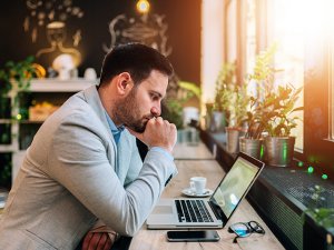 Thoughtful businessman looking at laptop screen.