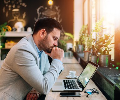 Thoughtful businessman looking at laptop screen.