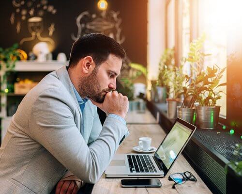 Thoughtful businessman looking at laptop screen.