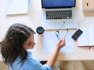 Young woman sitting in office table, looking at laptop computer screen . Young woman