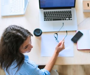 Young woman sitting in office table, looking at laptop computer screen . Young woman