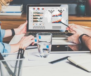 Businessman and businesswoman sitting at table in front of laptop and working. Graphs,charts and diagrams on PC screen.